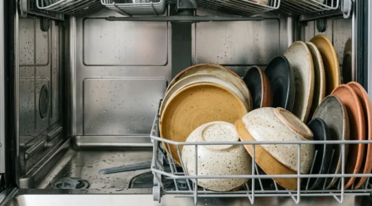 Assiettes en grès artisanal empilées dans un lave-vaisselle moderne
