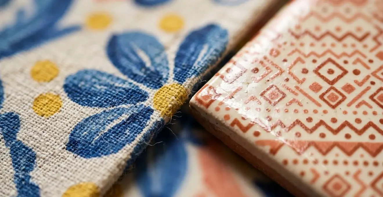 Gros plan macro sur le contraste entre un grand motif floral breton sur textile et un micro-motif géométrique sur céramique révélant les détails de texture