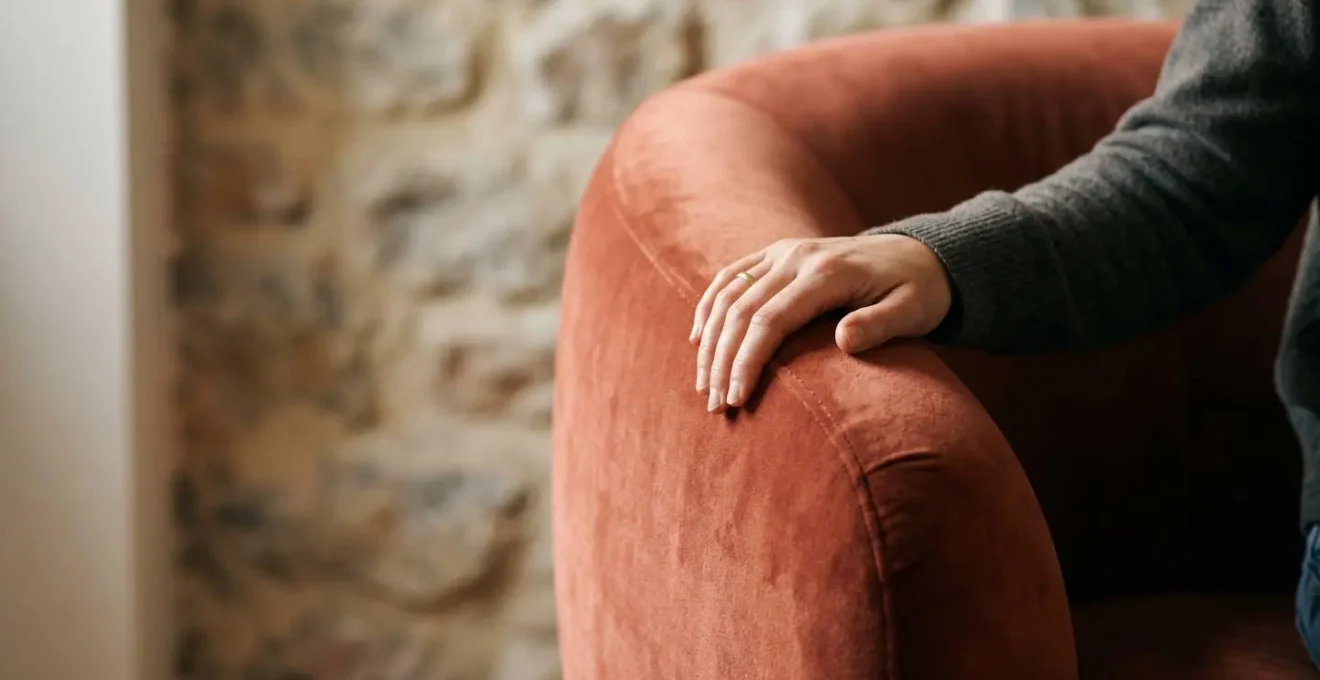 Fauteuil aux lignes courbes en velours devant un mur en pierre naturelle