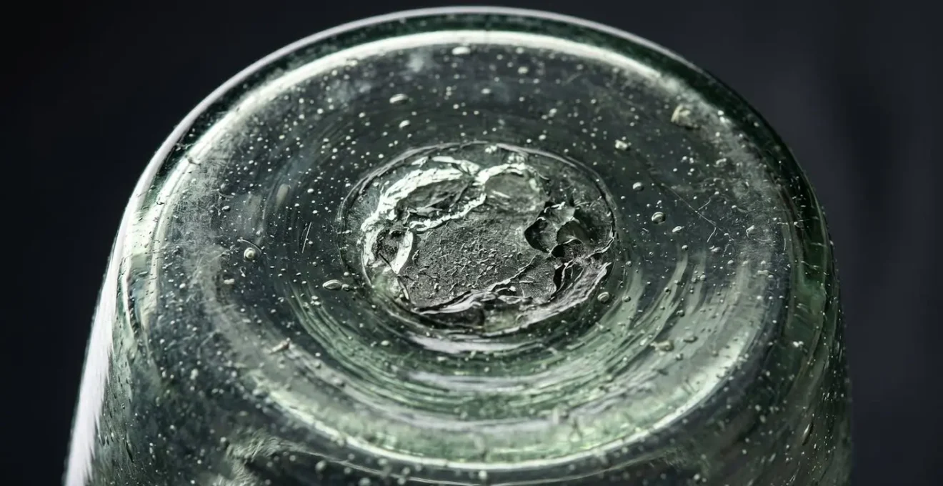 Détail macro du pontil et des bulles d'air dans un globe de verre soufflé à la bouche révélant sa fabrication artisanale