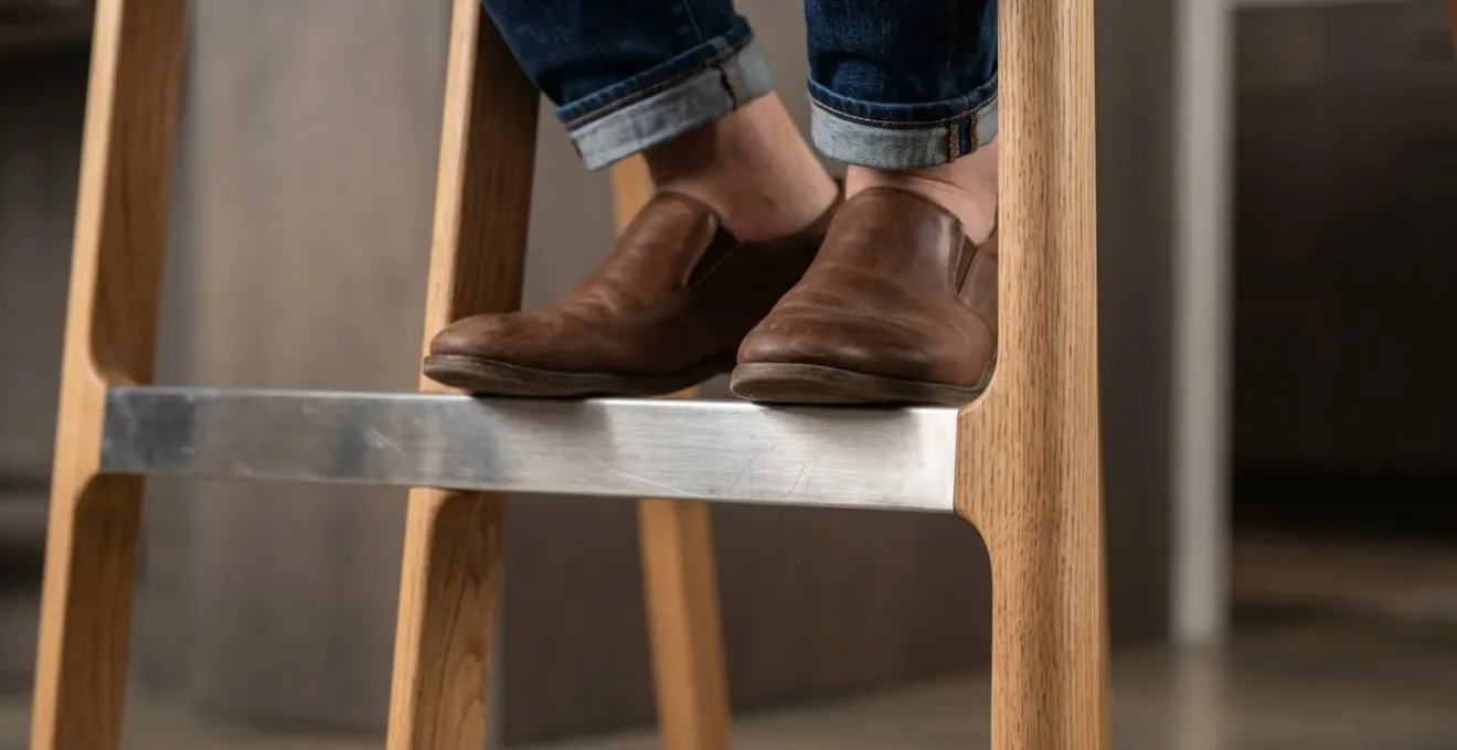Gros plan sur les jambes et repose-pieds d'un tabouret ergonomique près d'un îlot de cuisine